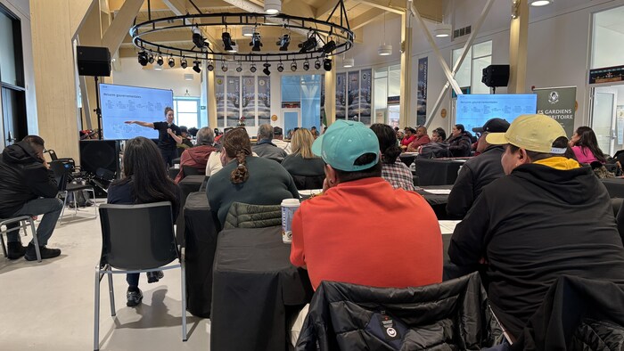 Des gens regardent une présentation sur le caribou.