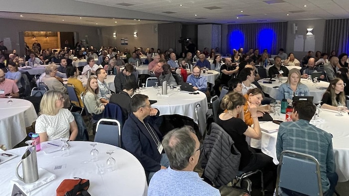 Des gens assis à des tables écoutent l'une des conférences du Forum.