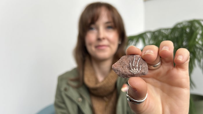 Anne MacFadyen montre le fossile, une patte de reptile incrustée dans une pierre.