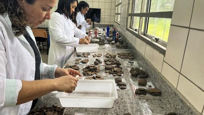 Arqueólogos examinam fragmentos de cerâmica encontrados durante escavações em um canteiro de obras em São Luís.