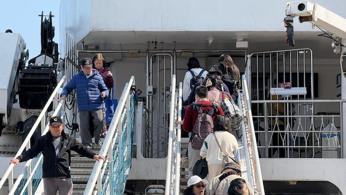 De nombreuses personnes entrent dans le navire et en sortent par des escaliers.