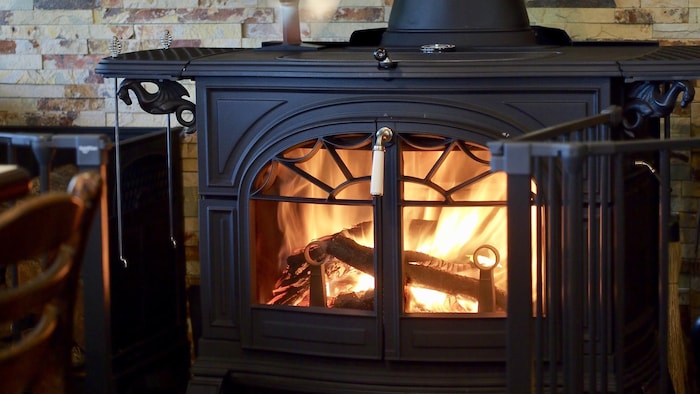 Un feu brûle dans un poêle à bois en fonte noire.