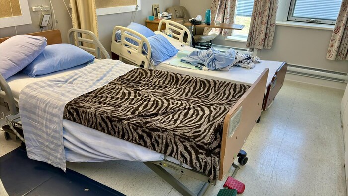 Deux lits d'hôpital dans une chambre, situés très près l'un de l'autre.