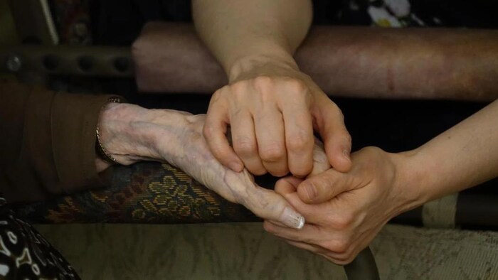 Une femme tient les mains d'une aînée.