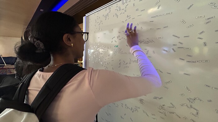 Une étudiante joue avec les mots du tableau.