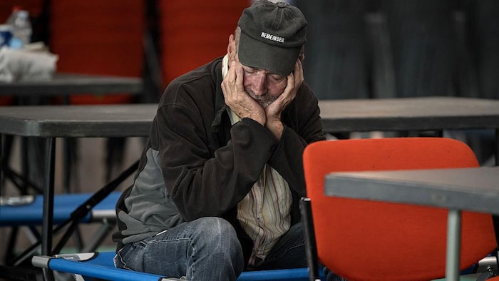 Un homme se repose avec la tête dans les mains, au centre converti pour accueillir les déplacés.