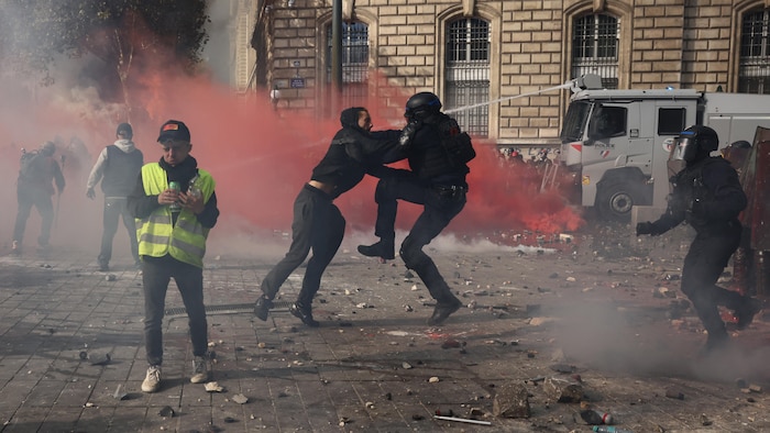 Un manifestant affronte un agent de la police antiémeute française.