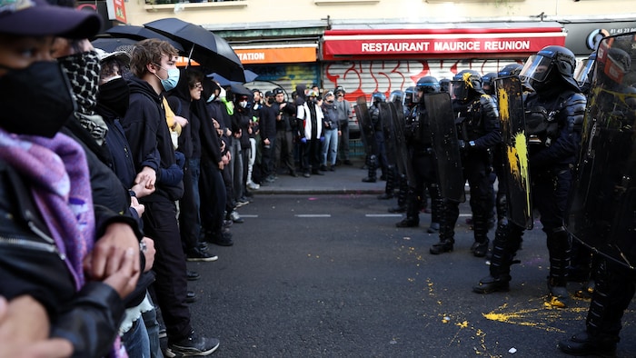Des manifestants masqués forment une chaîne humaine face aux forces d’intervention françaises lors d’une manifestation.