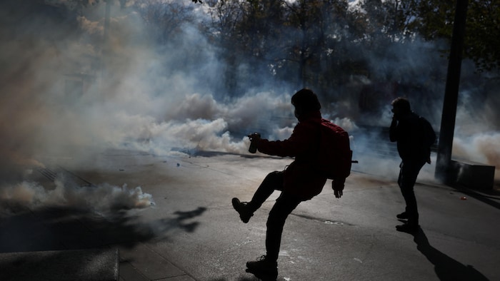 Des manifestants réagissent face aux gaz lacrymogènes lors d’affrontements avec la police.