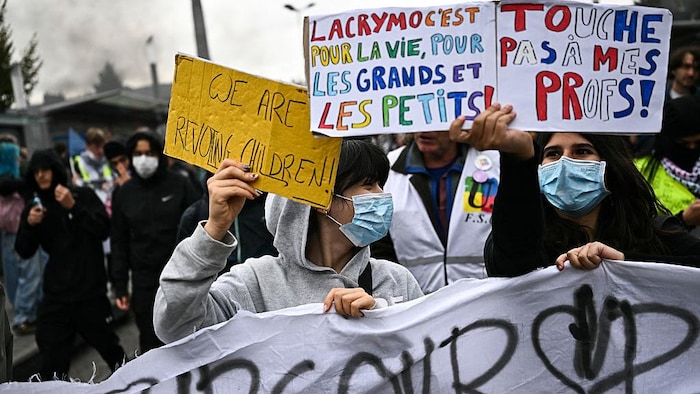 Les manifestants brandissent des pancartes sur lesquelles on peut lire « Les gaz lacrymogènes, c’est pour la vie, pour les adultes comme pour les enfants » et « Ne touchez pas à mes enseignants ».