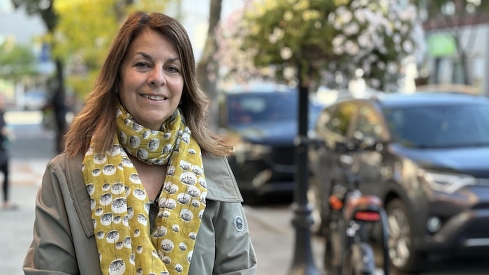 France Marion pose dehors sur le trottoir en face des bureaux de Radio-Canada à Rouyn-Noranda.