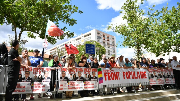 People wait behind barricades decorated with new Popular Front posters.