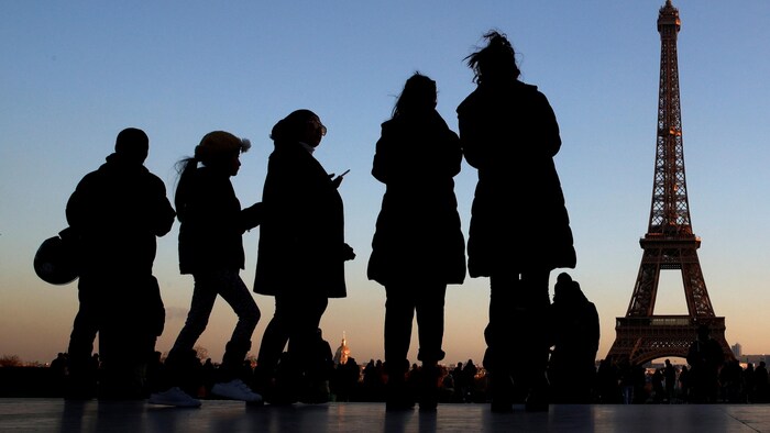 Des gens se tiennent sur la place du Trocadéro près de la Tour Eiffel à Paris.