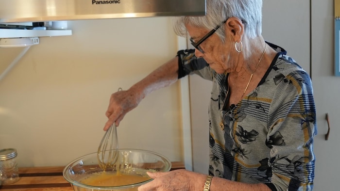 Une femme âgée prépare du sucre à la crème.