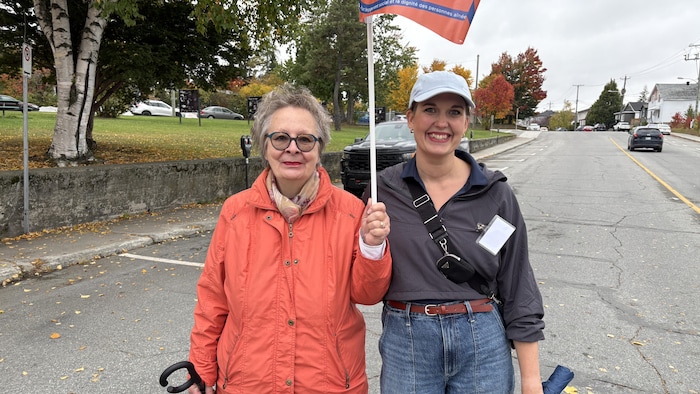 Francine Veillette-Plante et Jacinthe Doyon-Goyette posent pour la photo en pleine rue, un drapeau en main.