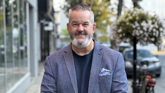 Francis Beauvais pose sur le trottoir pour la photo.