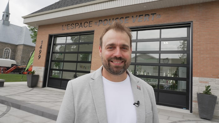 Un homme devant un édifice en brique avec deux portes de garage.