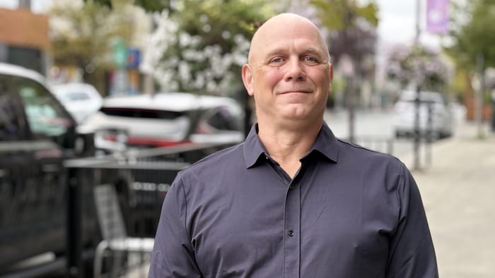 Francis Lapointe pose sur le trottoir en face du studio de Radio-Canada à Rouyn-Noranda.