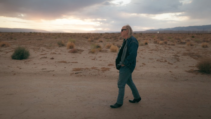 Un homme marche seul dans le désert alors que le soleil commence à se coucher. 