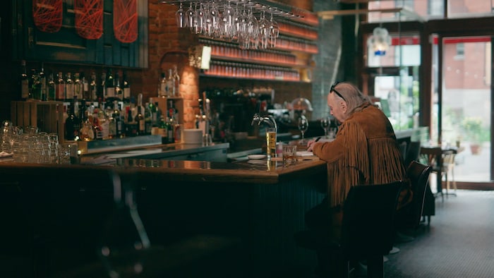 Un homme écrit, assis à un bar.