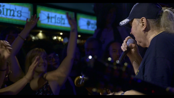 Un homme chante devant une foule dans un bar. 