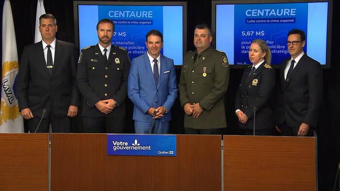 Six personnes, dont le ministre de la Sécurité publique, François Bonnardel (au centre), debout derrière un bureau.