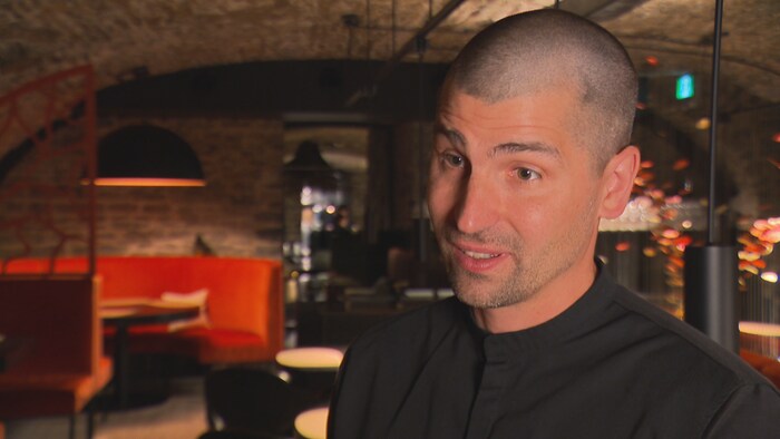 Il est en entrevue dans son restaurant.