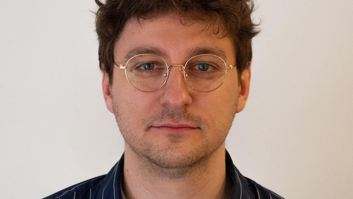 Un homme porte des lunettes dorées.