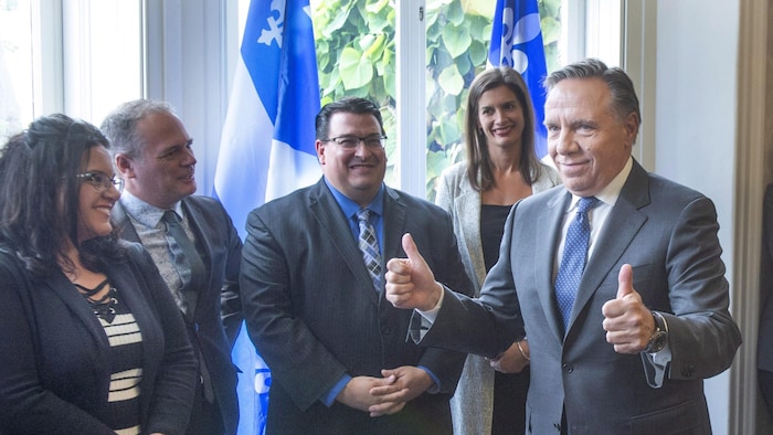 François Legault lève les deux pouces dans les airs en signe de victoire. Il est en compagnie de députés élus de la région de Québec. De gauche à droite se trouvent Émilie Foster, Jonatan Julien, Sylvain Lévesque et Geneviève Guilbault.