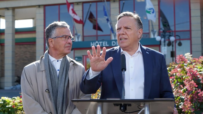 François Legault répond aux questions des journalistes devant l'Hôtel de Ville de Rouyn-Noranda en compagnie du candidat caquiste Daniel Bernard.