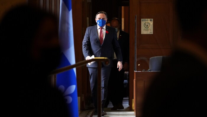 Le premier ministre François Legault, masqué, s'apprête à s'adresser aux journalistes.