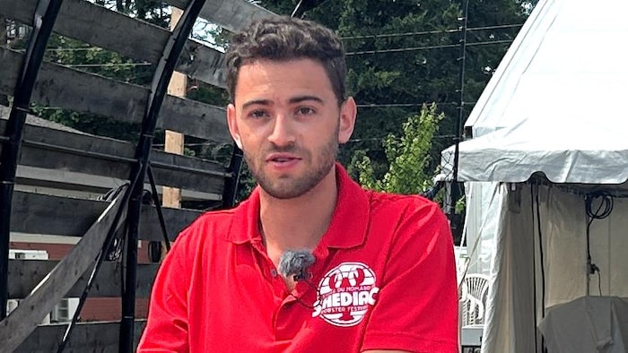 Un homme à l'extérieur, portant le t-shirt rouge officiel du festival.