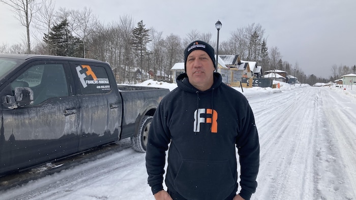 Un homme pose à côté de son camion.