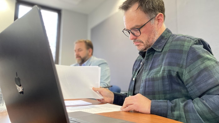 Un homme regarde des feuilles sur une table.