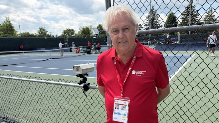 Un homme devant un terrain de tennis.