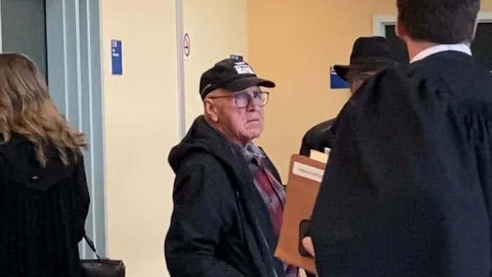 A 72-year-old man wears a hat and glasses.