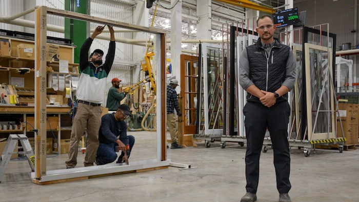François Xavier Bonneville debout dans l'usine où s'affairent des employés.