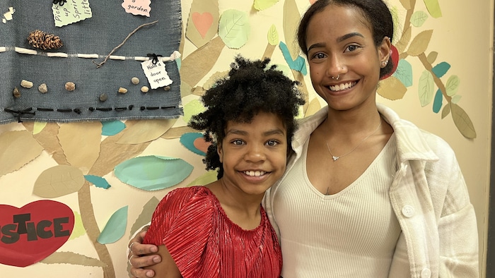 Deux sœurs se tiennent sur une photo en souriant.