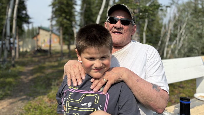 Un homme et son petit-fils sur un banc dans la forêt.