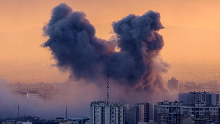 Un panache de fumée s'élève après une frappe sur la capitale iranienne, Téhéran au coucher du soleil.