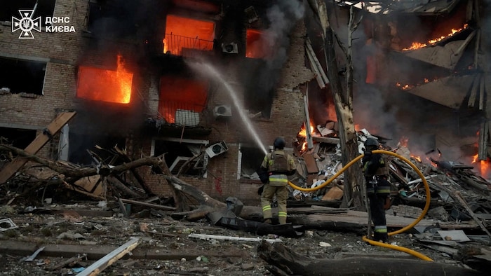 Des pompiers interviennent sur le site d'un bâtiment endommagé à Kiev.