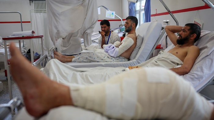Plusieurs personnes couchées dans des lits d'hôpital, certains portant des bandages.