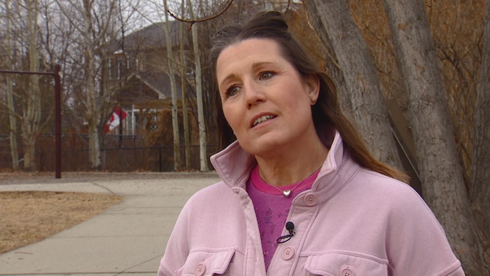 Stacey Schoneck se tient dehors, devant des arbres. 