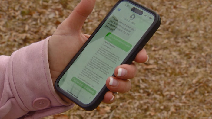 Une main tient un téléphone cellulaire. 