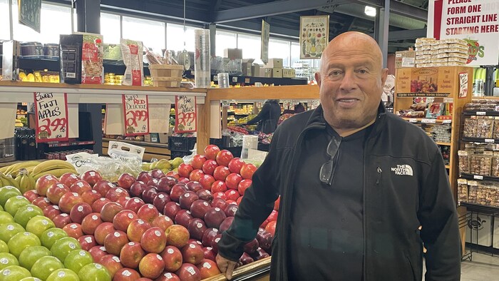Un homme devant un étalage de pommes.