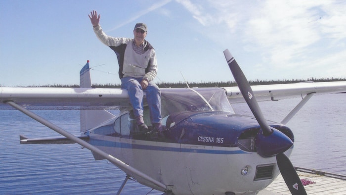 Fred Carmichael assis sur la carlingue de son Cessna.