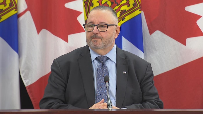 Fred Tilley assis à une table devant des drapeaux du Canada et de la Nouvelle-Écosse.