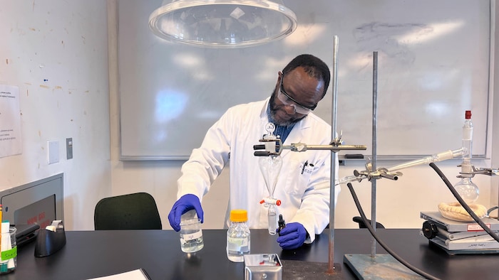 M. Muganza, en blouse blanche, avec des produits chimiques.
