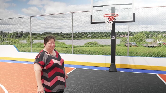 Une femme devant le panier de basketball.