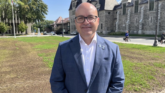Frédérik Boisvert pose, souriant, devant le manège militaire de Québec.
